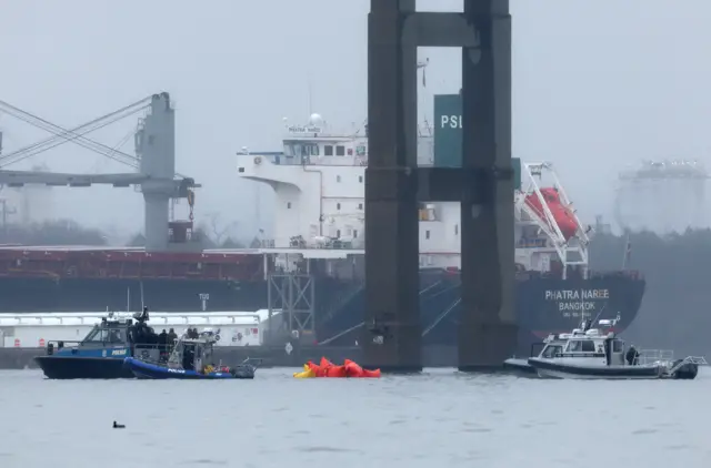 Emergency diver teams work with float bags towed by a police boat at the site of the wreckage