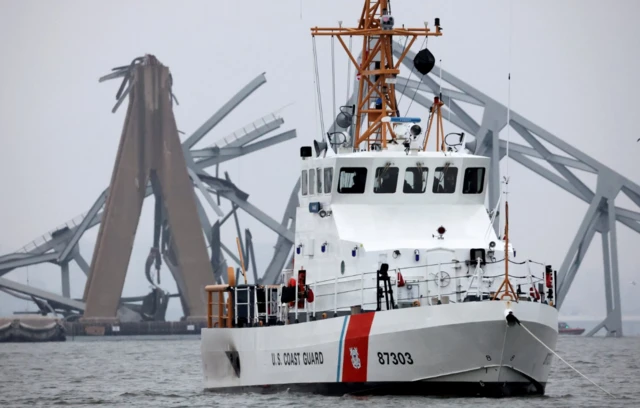 A US Coast Guard vessel sails near the Francis Scott Key Bridge, after the Dali cargo vessel crashed into it causing it to collapse - 24 March 2024