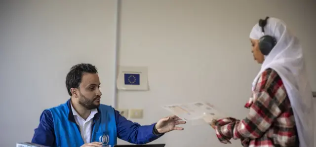 A UNHCR worker attends to an asylum seeker being sent from Libya to Rwanda