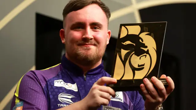 Luke Littler holds the Premier League night nine trophy