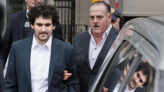 Cryptocurrency entrepreneur Sam Bankman-Fried (L) is lead out of an U.S. Federal Courthouse after being released on bail following an arraignment in New York, New York, USA, 22 December 2022.