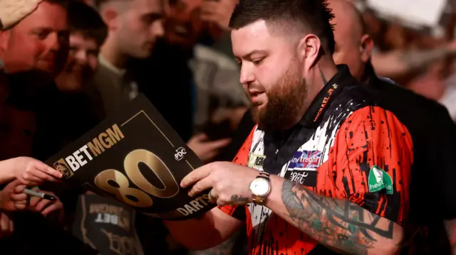 Michael Smith signs a sheet for a fan