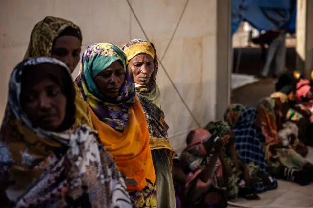 Sudanese refugees who have fled from the war in Sudan line up during a cash assistance programme at a Transit Centre for refugees in Renk, on February 15, 2024