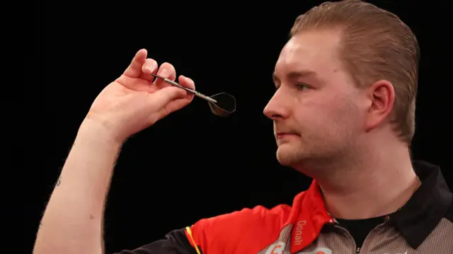 Dimitri Van den Bergh throws a dart