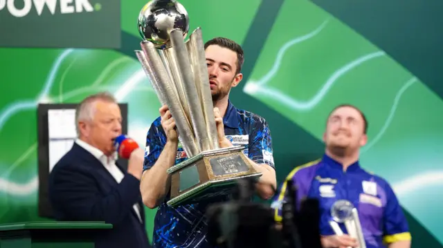 Luke Humphries holds the World Championship trophy