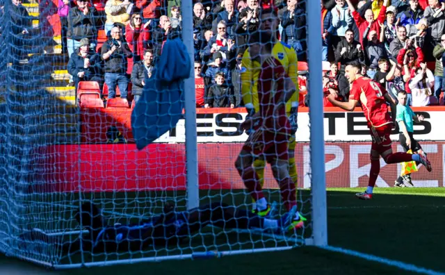 Aberdeen's Bojan Miovski celebrates as he finds his shot deflected by Ross County's Loick Ayina as he scores an own goal to make it 1-0 during a cinch Premiership match between Aberdeen and Ross County at Pittodrie Stadium, on March 30, 2024, in Aberdeen, Scotland.