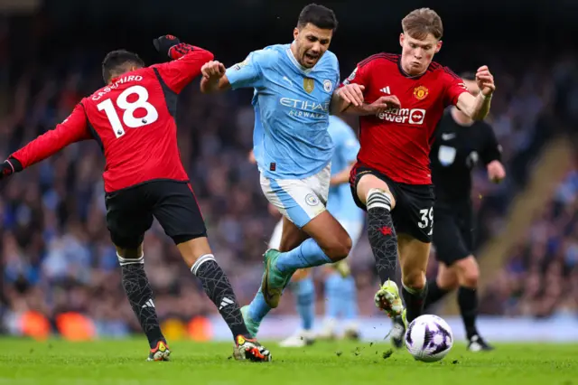 Manchester City midfielder Rodri battles with Manchester United players Casemiro and Scott McTominay