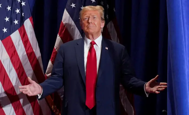 Donald Trump wearing a suit with both hands turned out