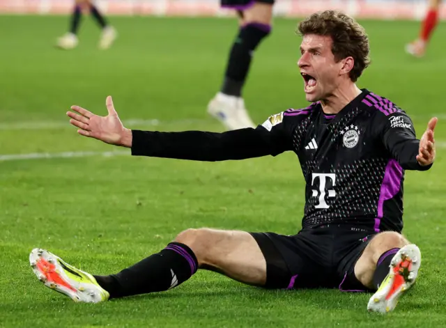 Muller remonstrates with the official while sat on the floor with his arms out wide.