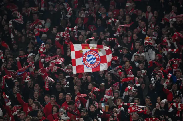 Bayern fans raise scarves and chant support from the stands.