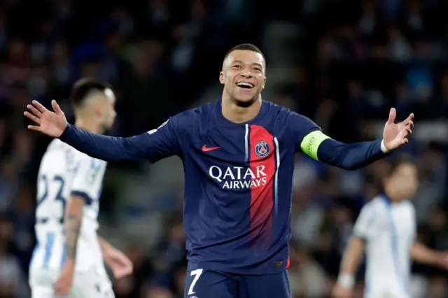 Mbappe holds his arms out wide and laughs in disbelief.