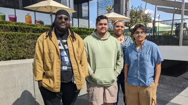 Four young people standing on a street