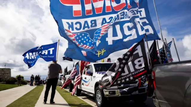 Supporters of Donald Trump get ready for a ''Primary Election Maga Cruise" rally, waving flags next a line-up of pick up trucks