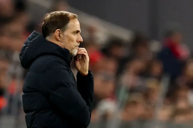 Tuchel is deep in thought with his chin in his hand.