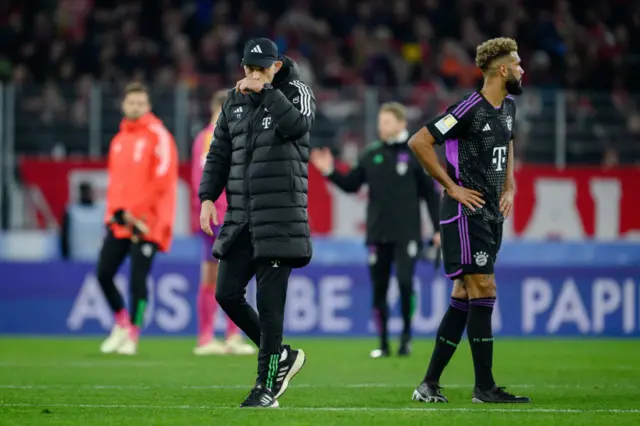 Tuchel wipes his face with his sleeve as he walks past one of his players.