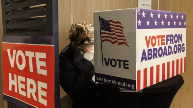 An US citizen, living in Switzerland, fills her ballot in the ballots box at the Super Tuesday of the Democrats Global Presidential primary voting, at a polling location situated in the Hotel Warwick in Geneva, Switzerland, 05 March 2024.