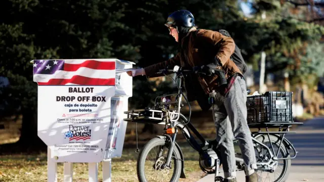 A voter submits their ballot at a ballot drop off box outside La Familia Recreation Center in Denver, Colorado,