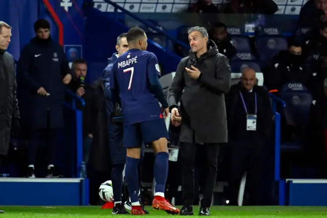 Enrique and Mbappe discuss tactics on the sidelines.