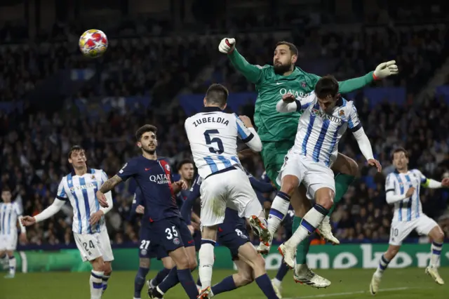 Donnarumma punches the ball above a packed penalty area.