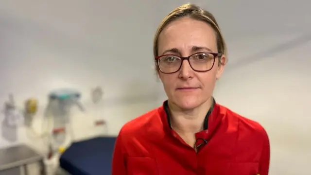 Anna Bell standing in red scrubs in a room at Southmead Hospital