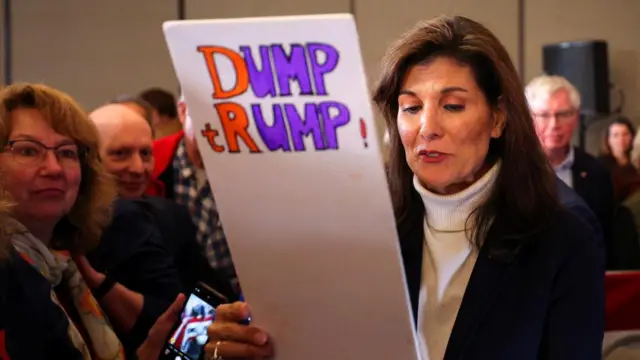 Nikki Haley reads a sign that says "Dump Trump" at one of her rallies