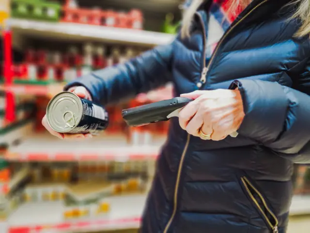 A woman holding a bar code scanner in the supermarket