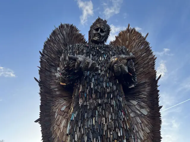 Knife angel sculpture with loads of old knives binded together with the blue sky in the background