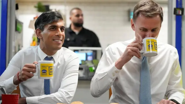 Rishi Sunak and British Chancellor Jeremy Hunt have a drink and biscuits during a visit to a builders