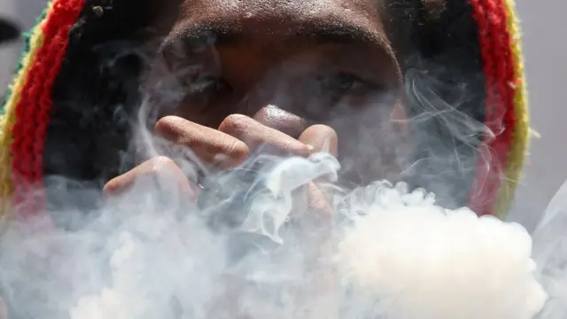 A person smokes in front of parliament during the annual Rastafari-led, Adwa and Salt River victory parade in Cape Town, South Africa.