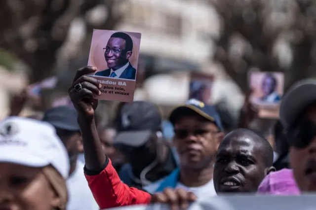 Supporters of the President of Senegal Macky Sall and presidential candidate Amadou Ba hold flyers carrying his portrait during a march for peace in Dakar on March 3, 2024.