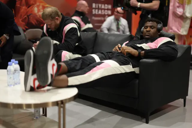 Francis Ngannou backstage with headphones on and his feet up