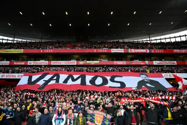 Arsenal fans hold up a banner reading "Vamos"