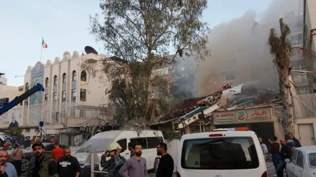 A group of men look around the site of the airstrike