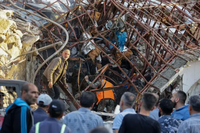 Emergency and security personnel inspect the rubble at the site of strike