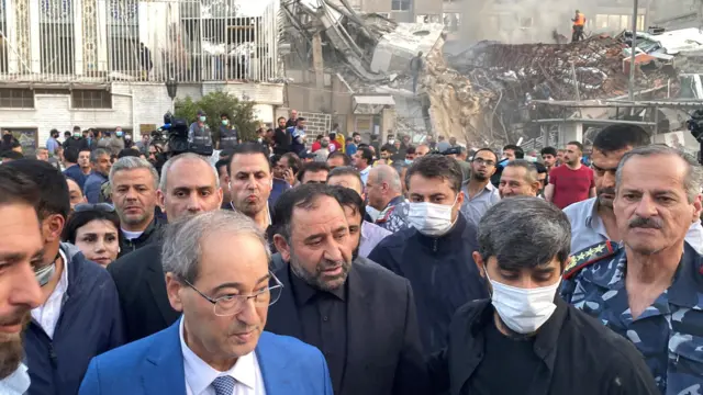 Syrian Foreign Minister Faisal Mekdad walks near a damaged site after what the Iranian media said was an Israeli strike on a building close to the Iranian embassy in Damascus, Syria