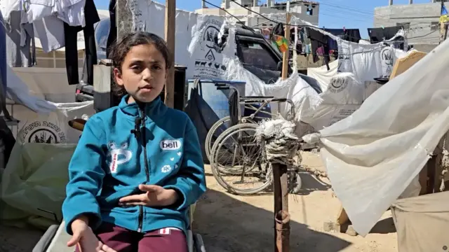 Tala Abu Amr, 7, sits in the middle of camp