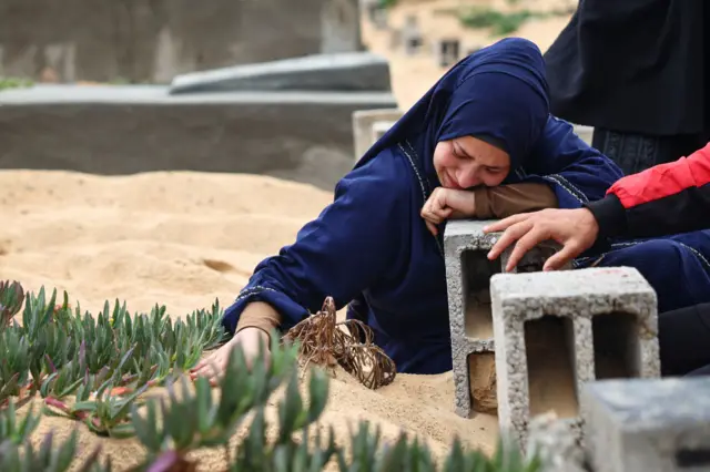 A woman cries over the grave of a loved one at the start of the Eid al-Fitr festival at a cemetary in Rafah in the southern Gaza Strip