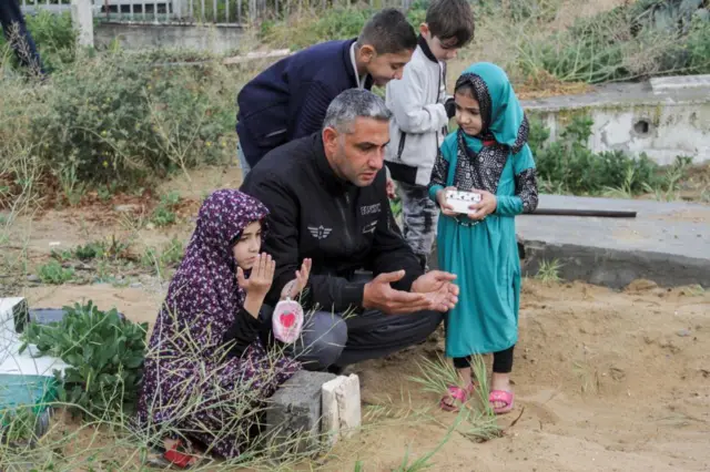 Palestinians visit the graves of people who were killed