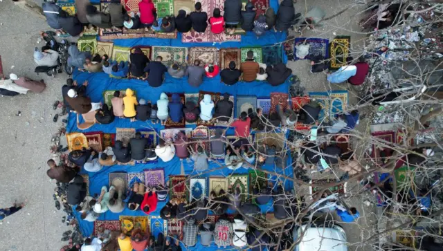 A drone view shows Palestinians holding Eid al-Fitr prayers by the ruins of al-Farouk mosque in Rafah