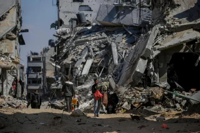 Families look at a bombed out tower block