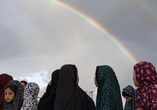 Palestinian girls perform Eid prayers in a camp in Rafah, southern Gaza on 10 April