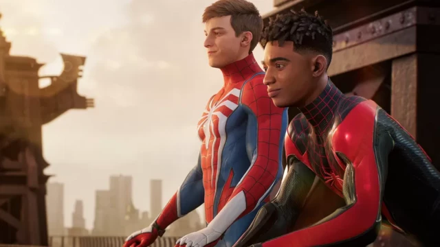 Suited up, Peter Parker and Miles Morales sit on the edge of a building.