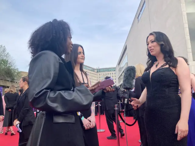 Two journalist talking to a woman on the red carpet