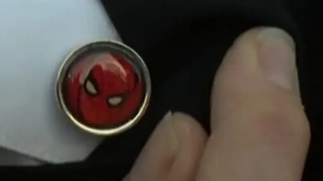 A cufflink bearing the face of Spider Man