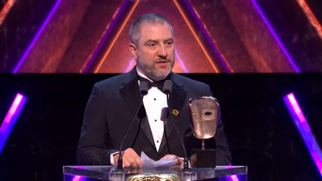 A man in a suit speaks at a lectern