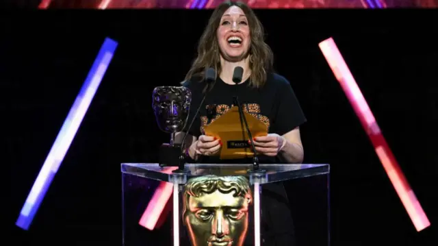 A blonde woman reads from the lectern