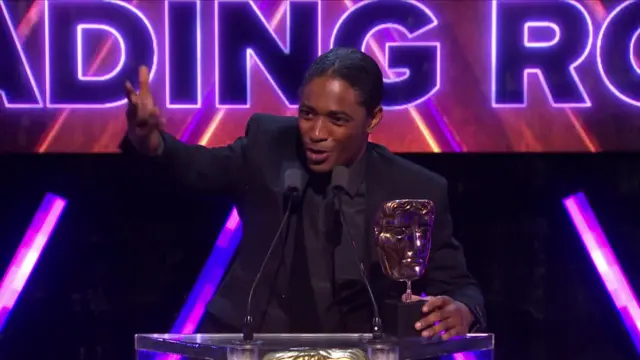 Nadji Jeter speaking on stage after collecting BAFTA Games Award