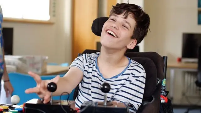 A boy using a specially made joystick to play a game.