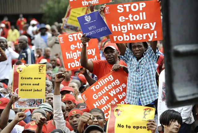 One among thousands of protestors holds a banner reading "Tolling Gauteng High Ways must be Scrapped" duirng a march through Johannesburg on March 7, 2012 to protest new tolls on highways between Johannesburg and nearby Pretoria and the practices of temp agencies, which unions say are hurting the poor.