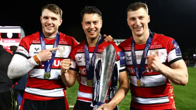 Ruan Ackerman (L) Lloyd Evans (C) and Alex Hearle (R) of Gloucester celebrate with the trophy following the final of the Premiership Rugby Cup